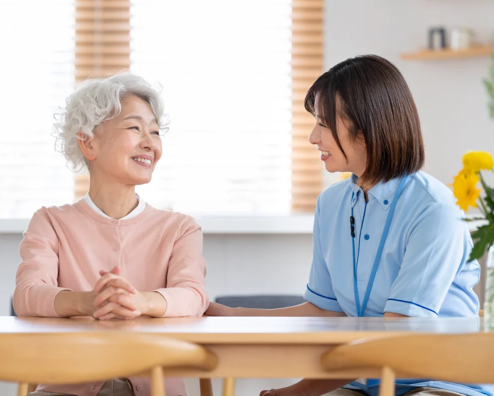 向かい合って会話する高齢の女性と介護スタッフ