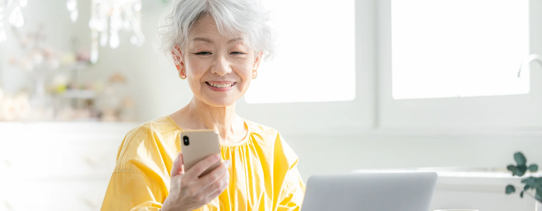 スマートフォンを見ながらほほえむ高齢の女性