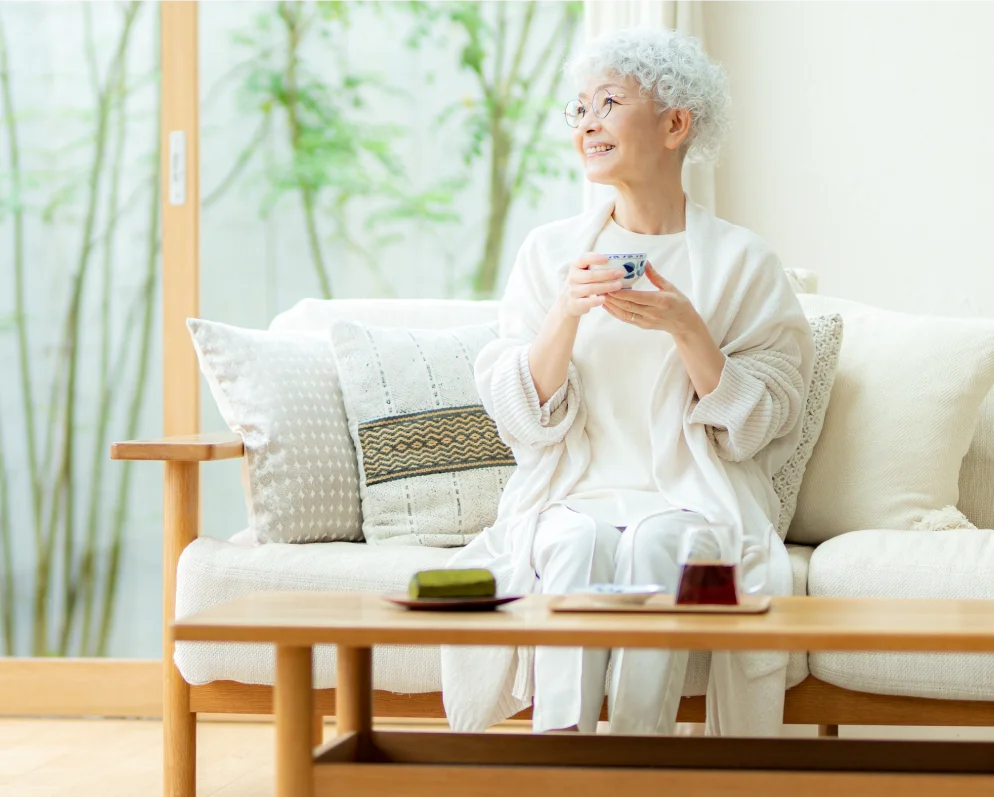 窓辺でお茶を楽しむ高齢の女性