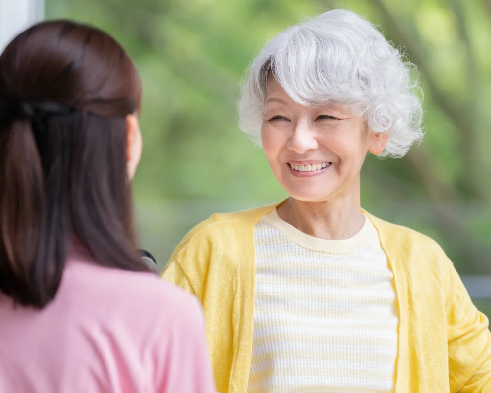 向かい合って会話する高齢の女性と女性スタッフ